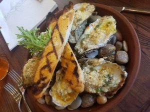 chargrilled oysters and french bread over a plate of hot rocks