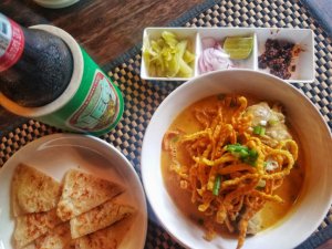 bowl of Khao soi with a beer and bread in Chiang Mai Thailand, the best place to travel in Southeast Asia for food