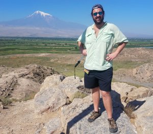 Hangry Backpacker standing on rocky outcrop with Mount Ararat in background, Armenia