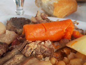 cocido in Madrid with a carrot on top of a pile of meat and chickpeas