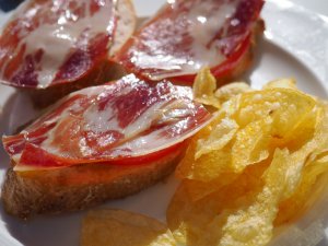 eating tapas in Madrid with jamon on bread and potato chips