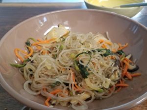 bowl of homemade Korean glass noodles with spinach and shredded carrots