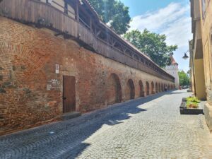 Medieval stone and brick city walls with covered wooden structure on top in Sibiu Romania