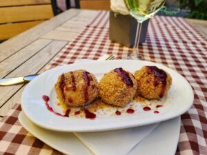 Romanian plum dumplings in Brasov with glass of white wine