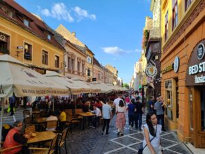 crowded street with people sitting at tables and walking in Brasov