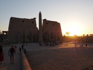 Entrance of Luxor Temple with the sun setting over the Nile in Egypt